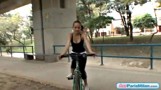 Busty teen riding her bike through the park