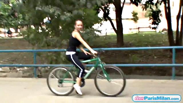 Busty teen riding her bike through the park