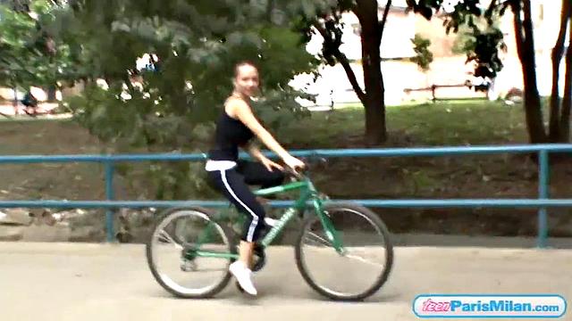 Busty teen riding her bike through the park
