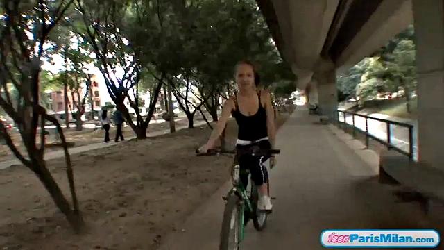 Busty teen riding her bike through the park