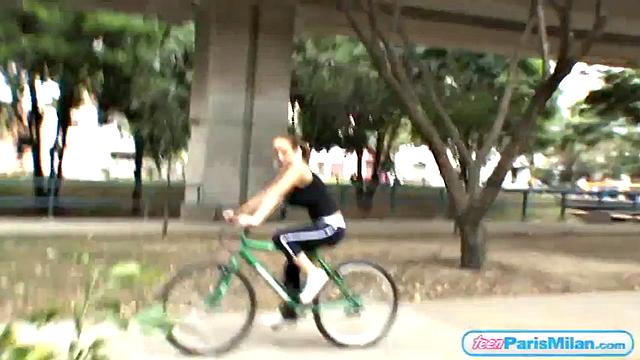 Busty teen riding her bike through the park