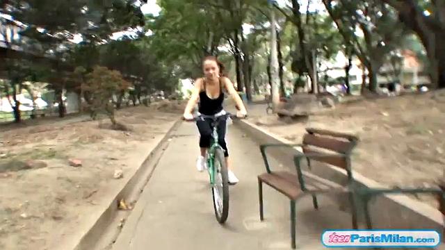 Busty teen riding her bike through the park