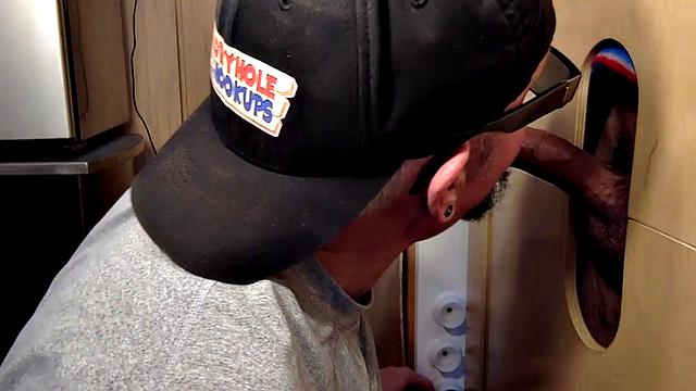 Gloryhole inked DILF sucks BFs cock through hole at home