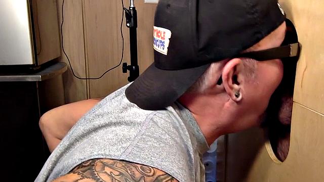 Gloryhole inked DILF sucks BFs cock through hole at home