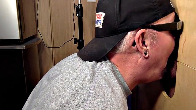 Gloryhole inked DILF sucks BFs cock through hole at home