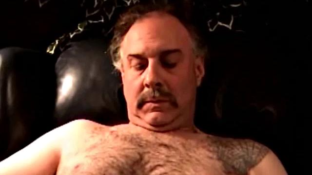 Robert is a dump truck driver and has that big hairy bear look. He's a simple and very pleasant guy to be around. He likes getting his dick sucked and will sometimes return the favor. In this solo, he gets naked, sits in a chair and jacks off.