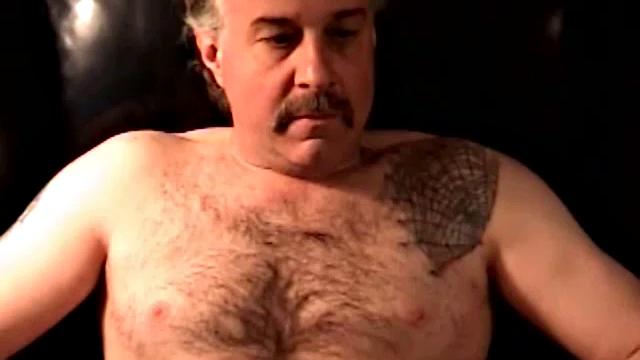 Robert is a dump truck driver and has that big hairy bear look. He's a simple and very pleasant guy to be around. He likes getting his dick sucked and will sometimes return the favor. In this solo, he gets naked, sits in a chair and jacks off.