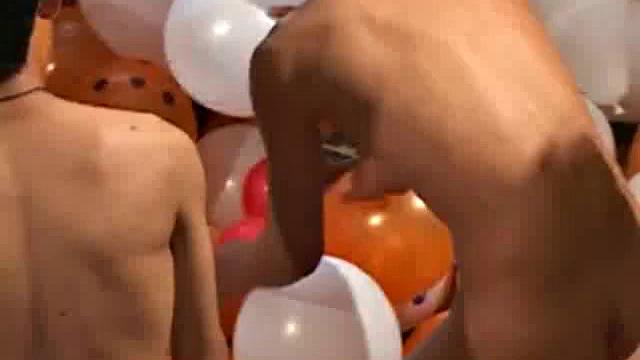 Eight boys play a game of strip balloons where a giant dice determines who undresses