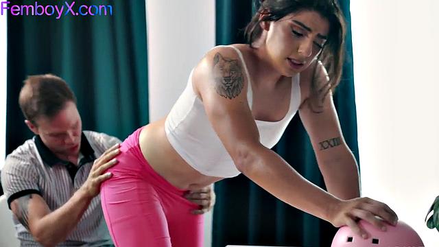 фембой с длинными волосами растягивает жопу на йоге с тренером