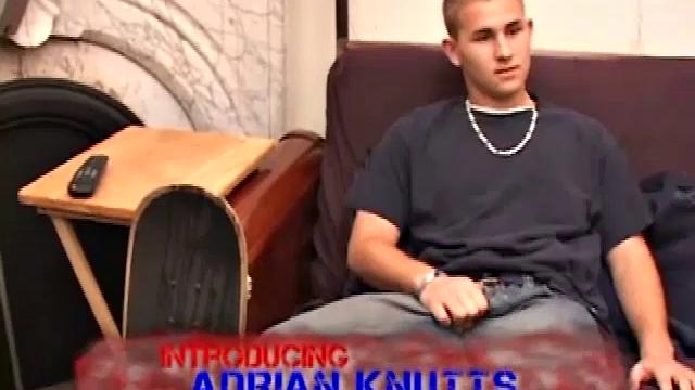 After stripping naked, Adrian Knutts works the remote control, as he strokes his cock to the porn flick that's playing. He sticks a finger up his ass to help him get closer, before shooting a big warm load onto his chest and face.