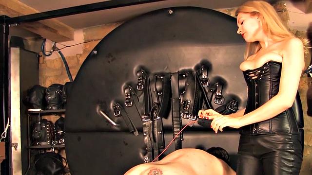 Whipping domina in leather harasses sub in e-stim.