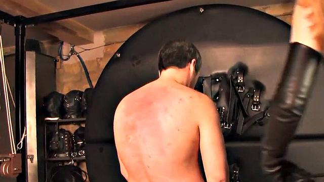 Leather BDSM domina whipping her sub in lesson