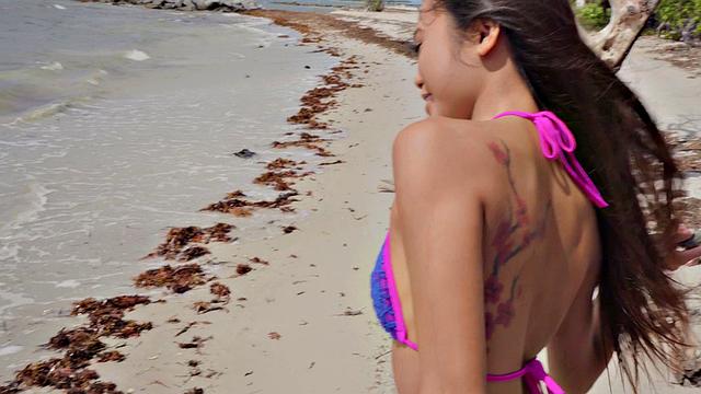 Kinky tattooed brunette gets wet and wild on the beach with a ball in her mouth and pussy