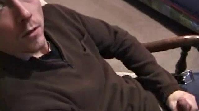 By the time the camera finds him, Dan is already going for his woody. A bit uncomfortable in the chair, he stands up and moves to the staircase, where we can see his hot cock getting harder and harder.